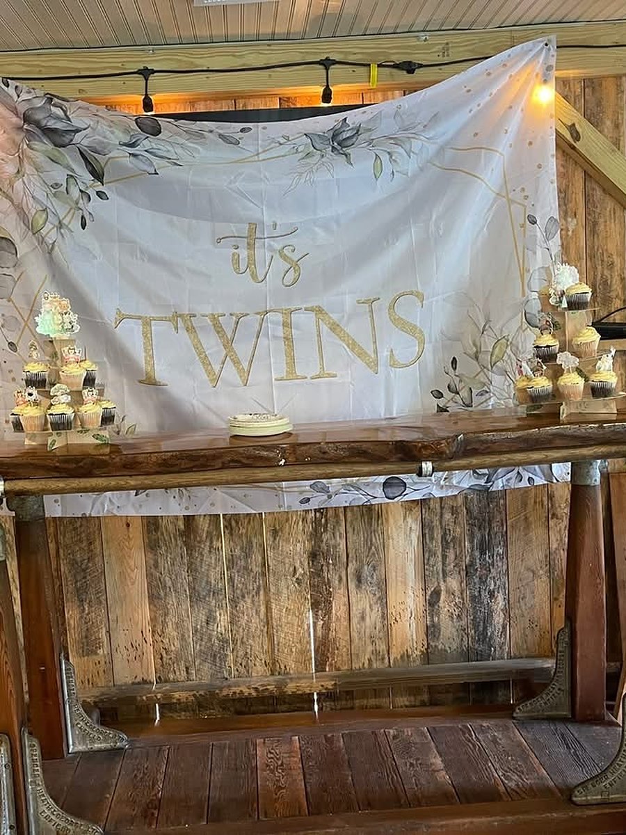 Twins baby shower set up at the rustic barn bar with string lights, cupcakes and an It’s Twins banner at Riverside Farm Venue